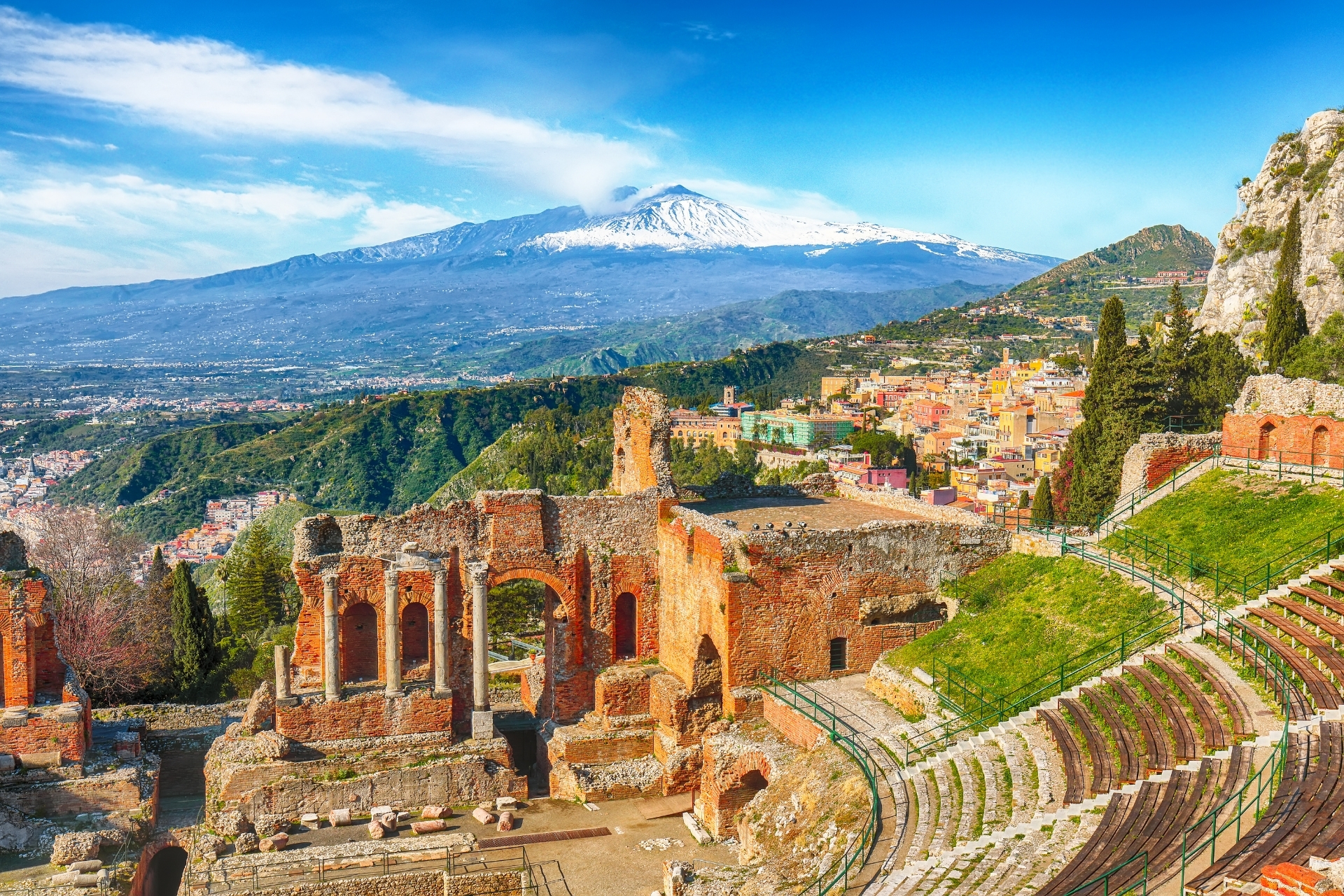 The ancient Greek Theatre of Taormina overlooking the Ionian Sea with Mount Etna in the background.