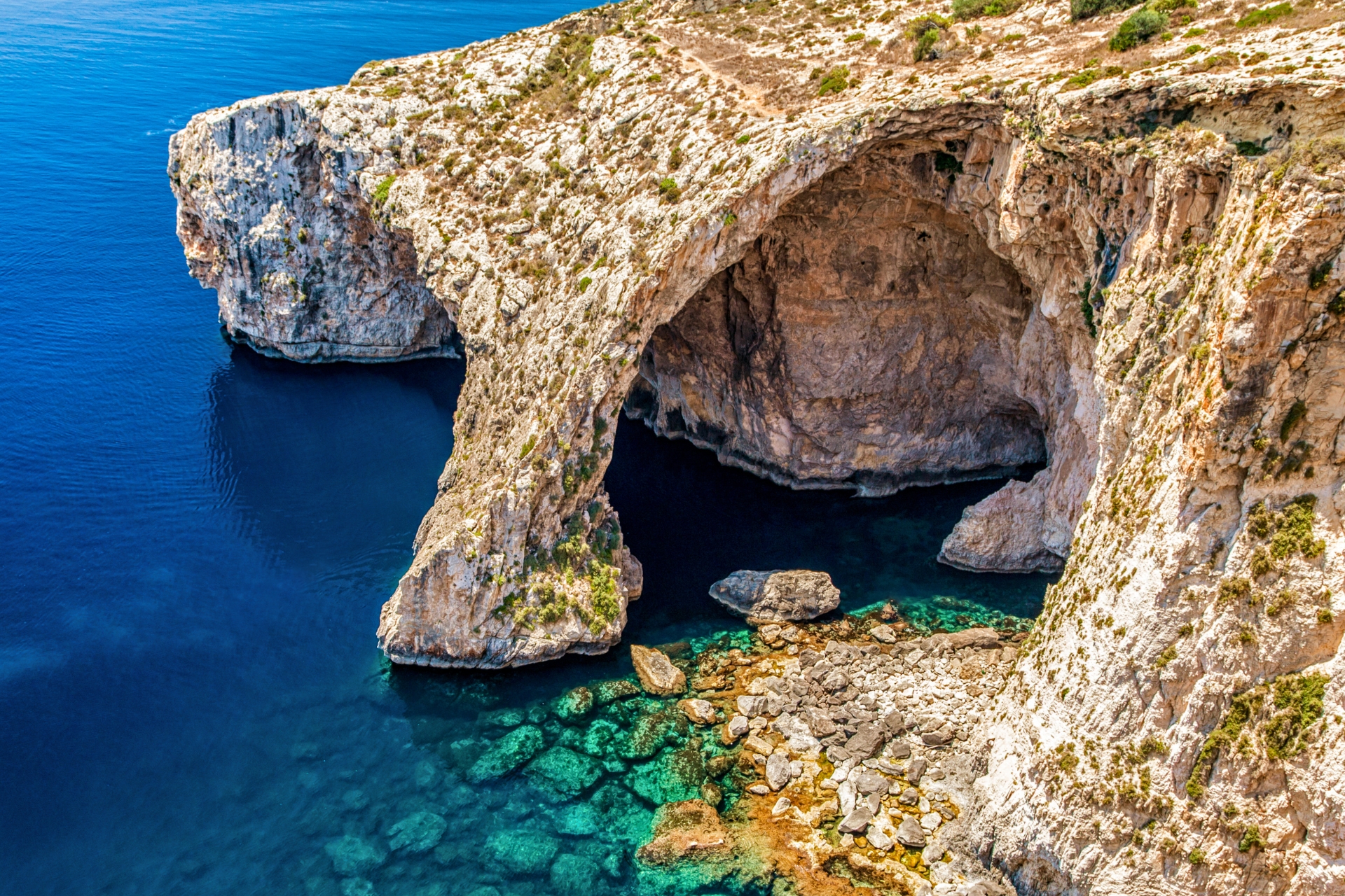 The Blue Grotto on Malta's southern coast, featuring dramatic limestone cliffs and crystal-clear blue waters.