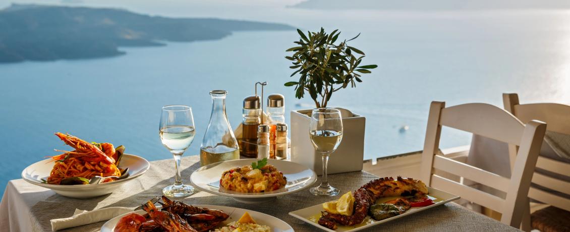 Delicious seafood meal served with wine in front of Mediterranean seashore. 