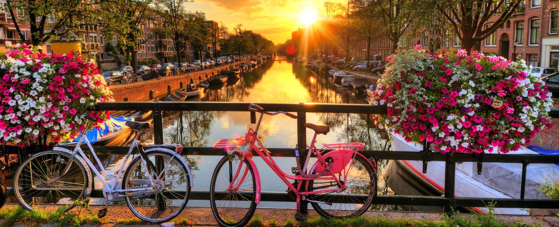 Sunset over Amsterdam's canals with two colourful bikes infront of a bridge