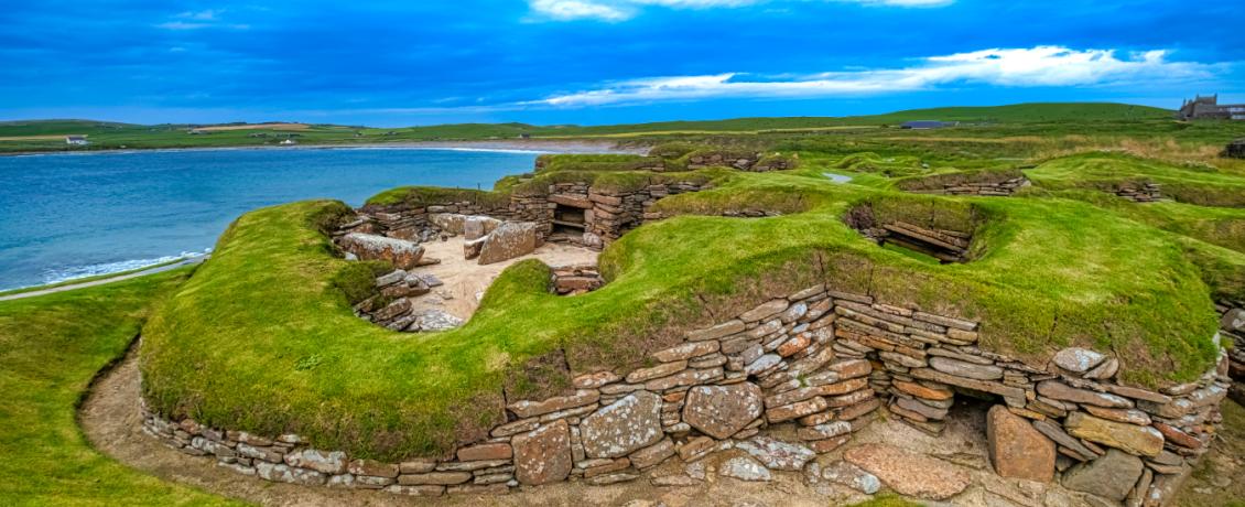 Prehistoric village of Skara Brae on the windswept Orkney Islands, its Stone Age dwellings emerging from grassy mounds.