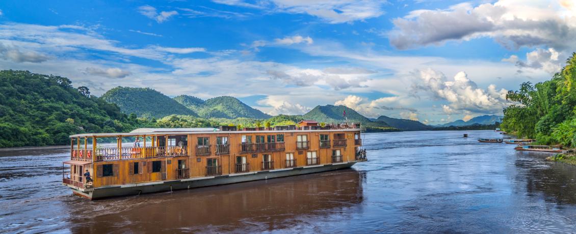 A cruise ship traveling down the Mekong River, surrounded by beautiful scenery