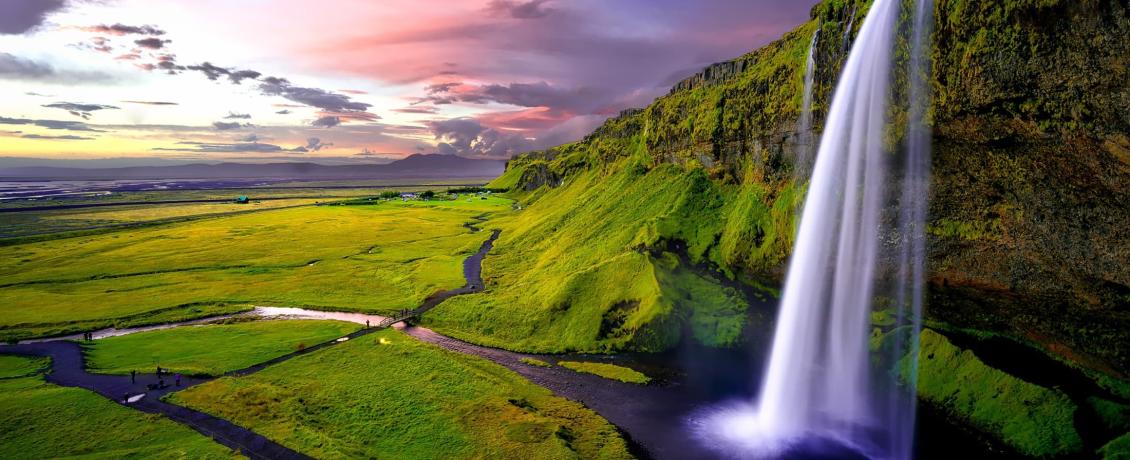 A powerful waterfall, Seljalandsfoss, cascades down a cliff into a pool of water in Iceland.