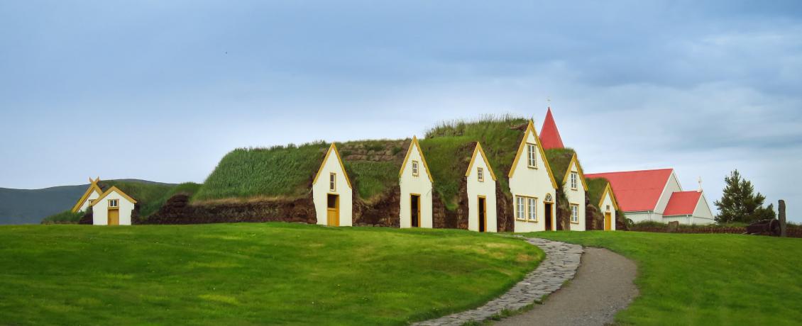 Turf houses at Glaumbær, an open-air museum in Iceland, with grass roofs and a red-roofed church in the background