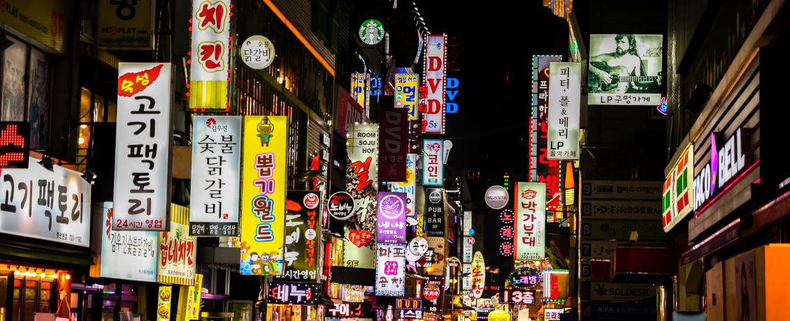 People walking in the sea of neon advertisement boards in Myeongdong Seoul South Korea.