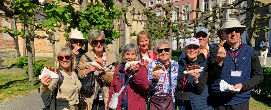 Group of Craig Travel guests smiling and holding Belgian waffles