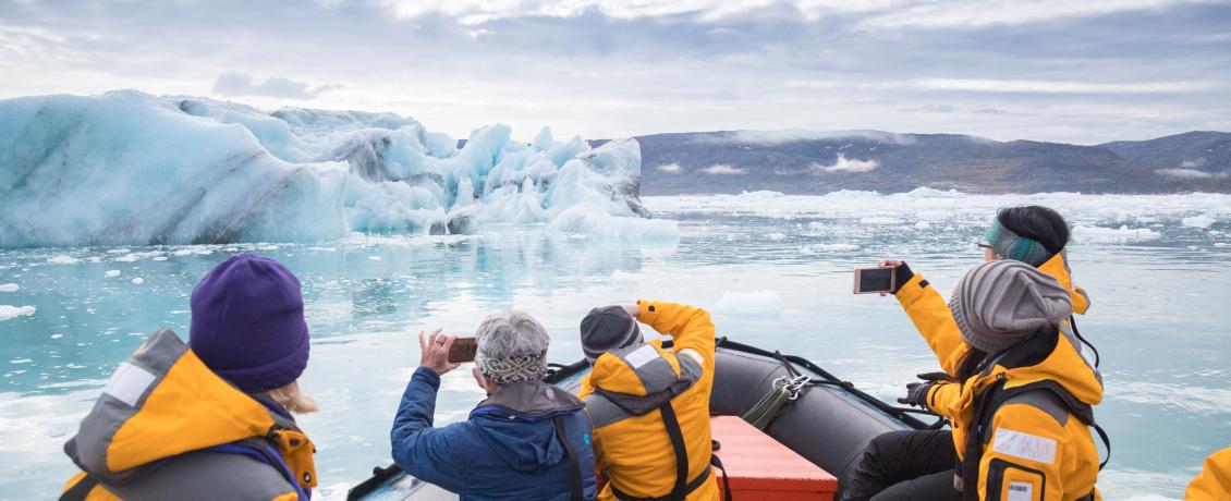 Passengers in expedition jackets photographing glacier and icebergs from Zodiac