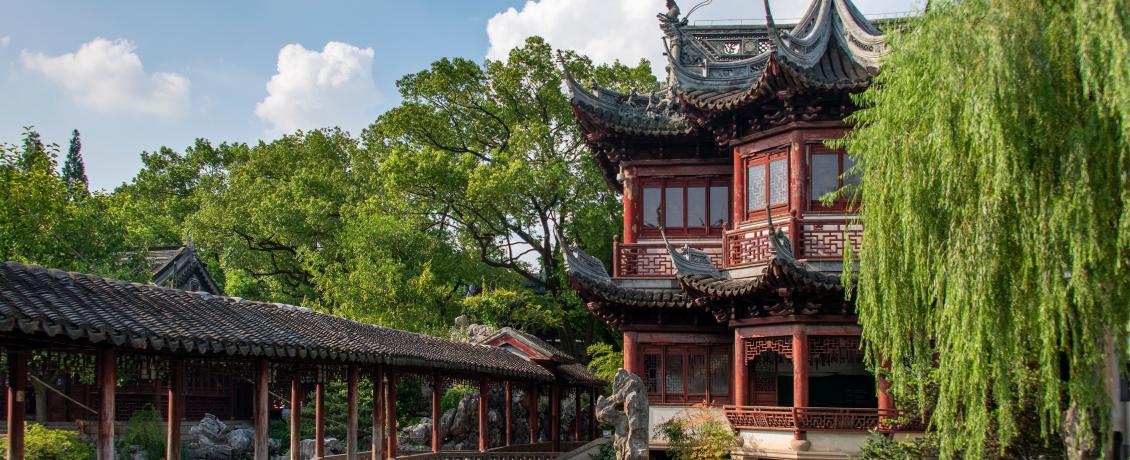Traditional Chinese pavilion and covered walkway beside a garden pond.