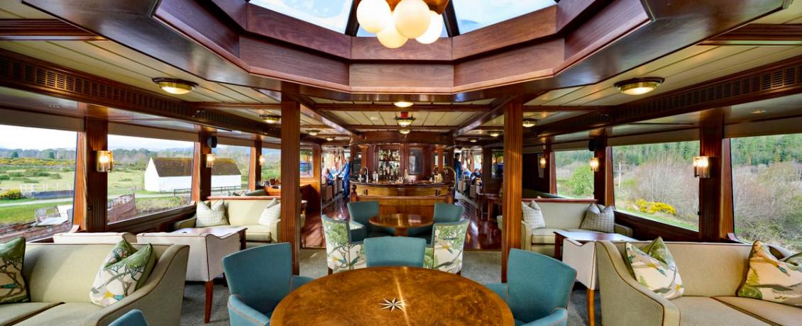 Lounge aboard the Lord of the Glens with panoramic windows, comfortable seating, and warm wood interiors.