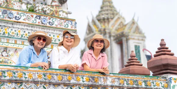 Three smiling women visiting a Thai temple